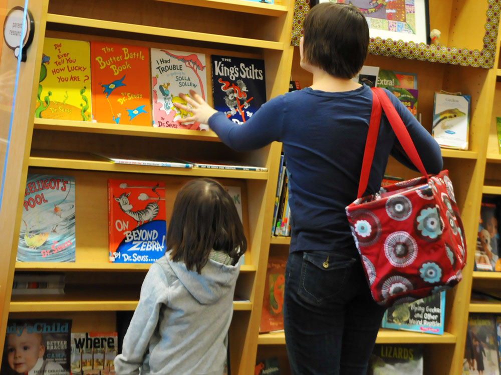 Child and grown-up looking at books on a shelf in infoZone.